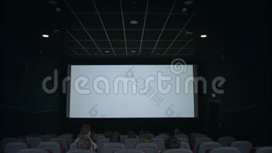 观众在电影院大厅观看白色屏幕，期待电影放映